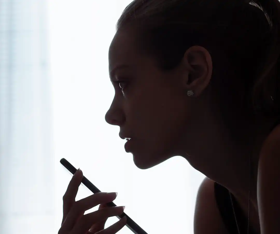 A woman using her cell phone, highlighting the role of voice search in AI search platforms.